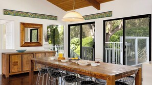Una cocina moderna con una mesa de madera, sillas de metal y ventanas amplias.