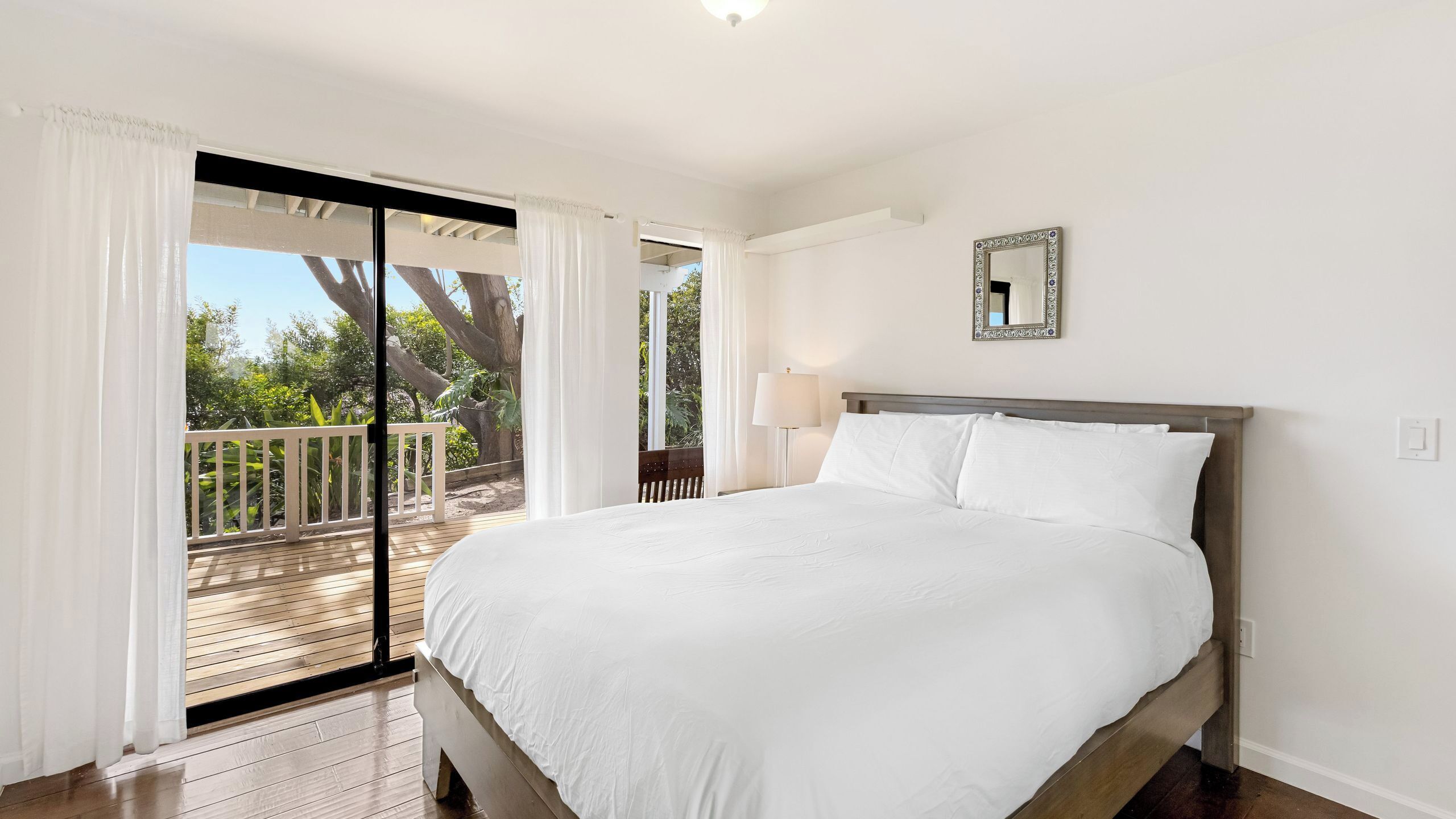 Un dormitorio con una cama grande, un balcón y vistas a árboles.
