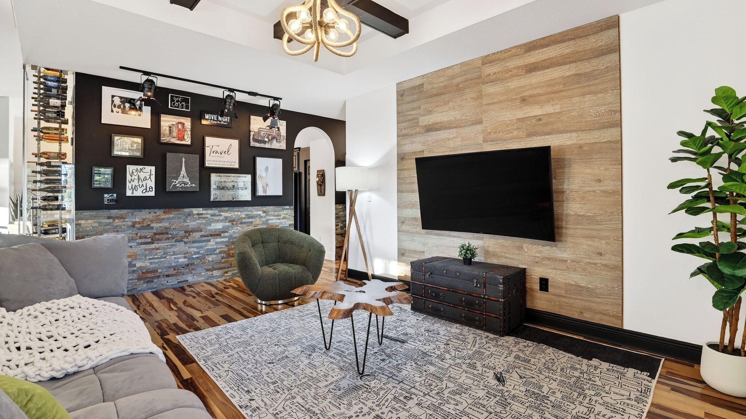 A modern living room with a fireplace, a mounted TV, and a variety of wall art.