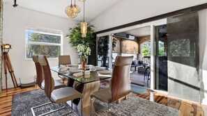 A modern dining area with a glass table, wooden chairs, and a potted plant.