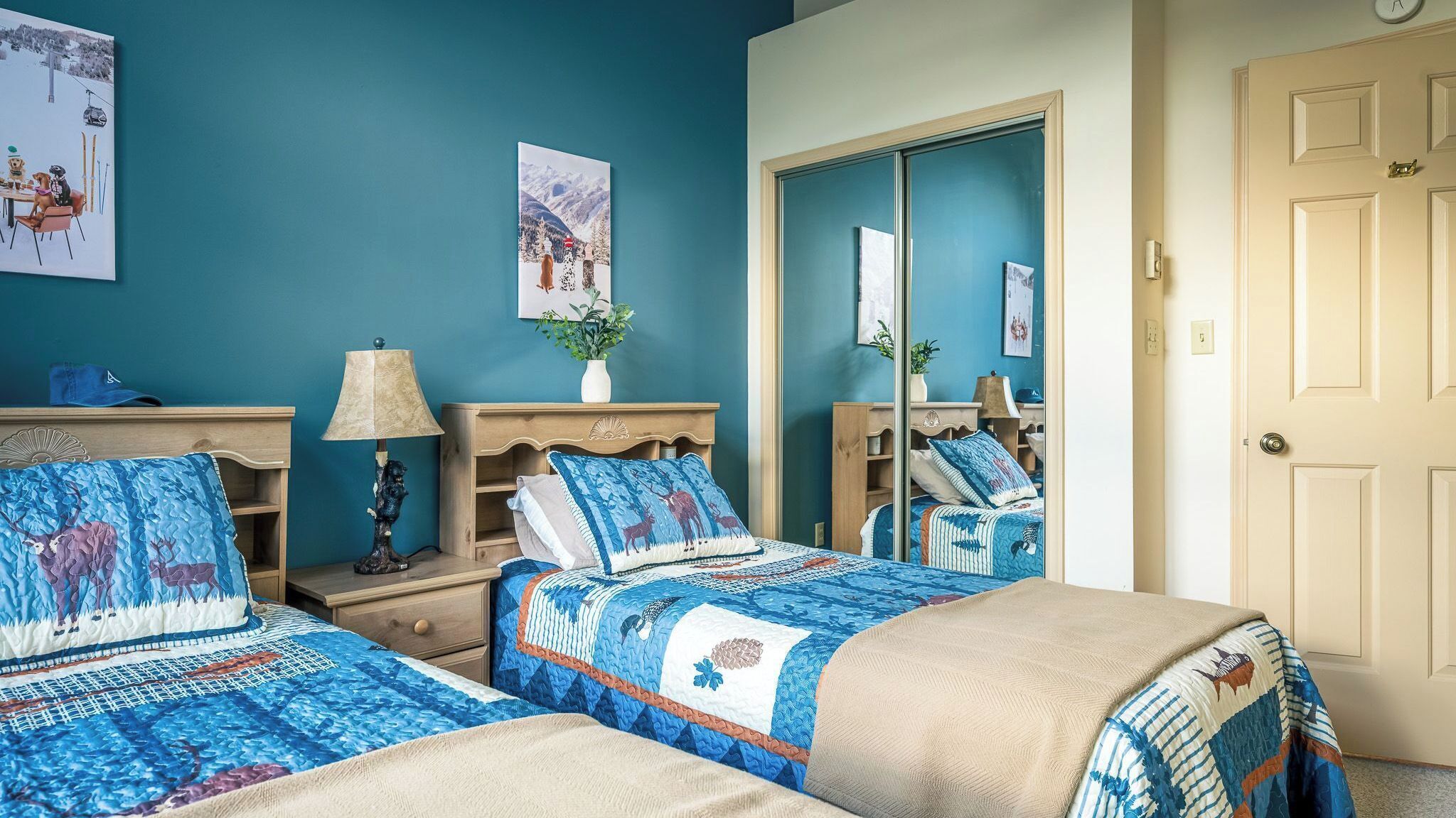 A bedroom with two beds, a nightstand, a lamp, a dresser, and a mirror.