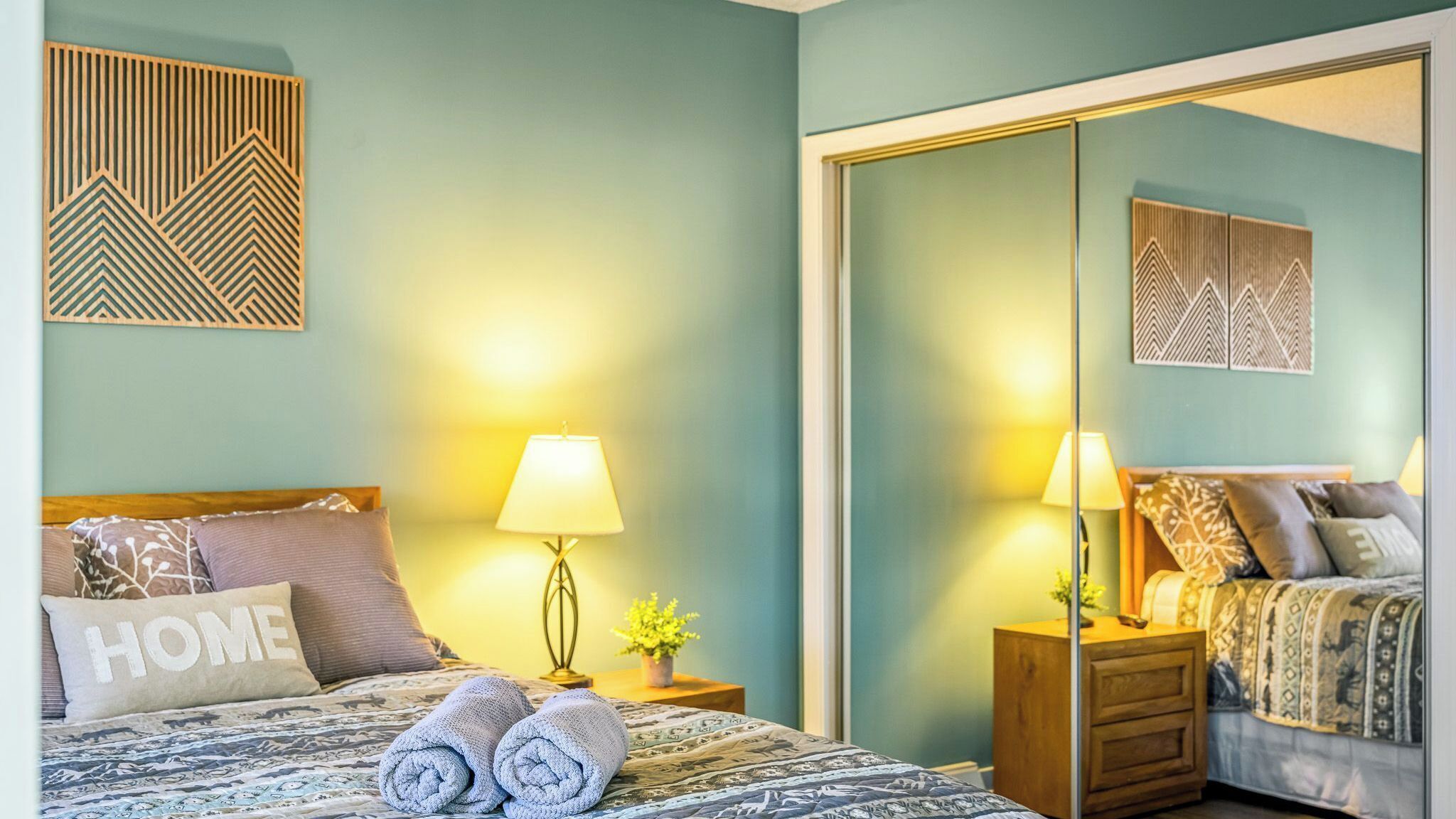 Une chambre à coucher comprenant un lit, deux tables de chevet, un miroir et une armoire.