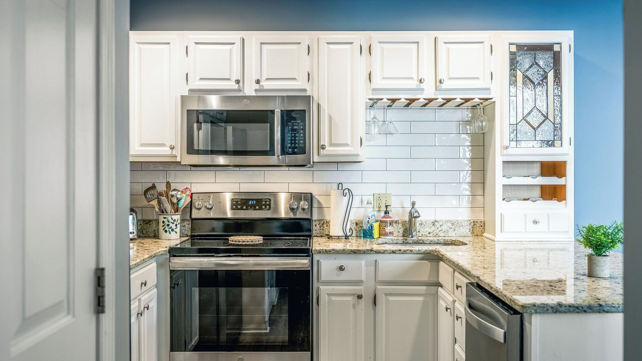 A kitchen with white cabinets, a stainless steel microwave, an oven, and a granite countertop.