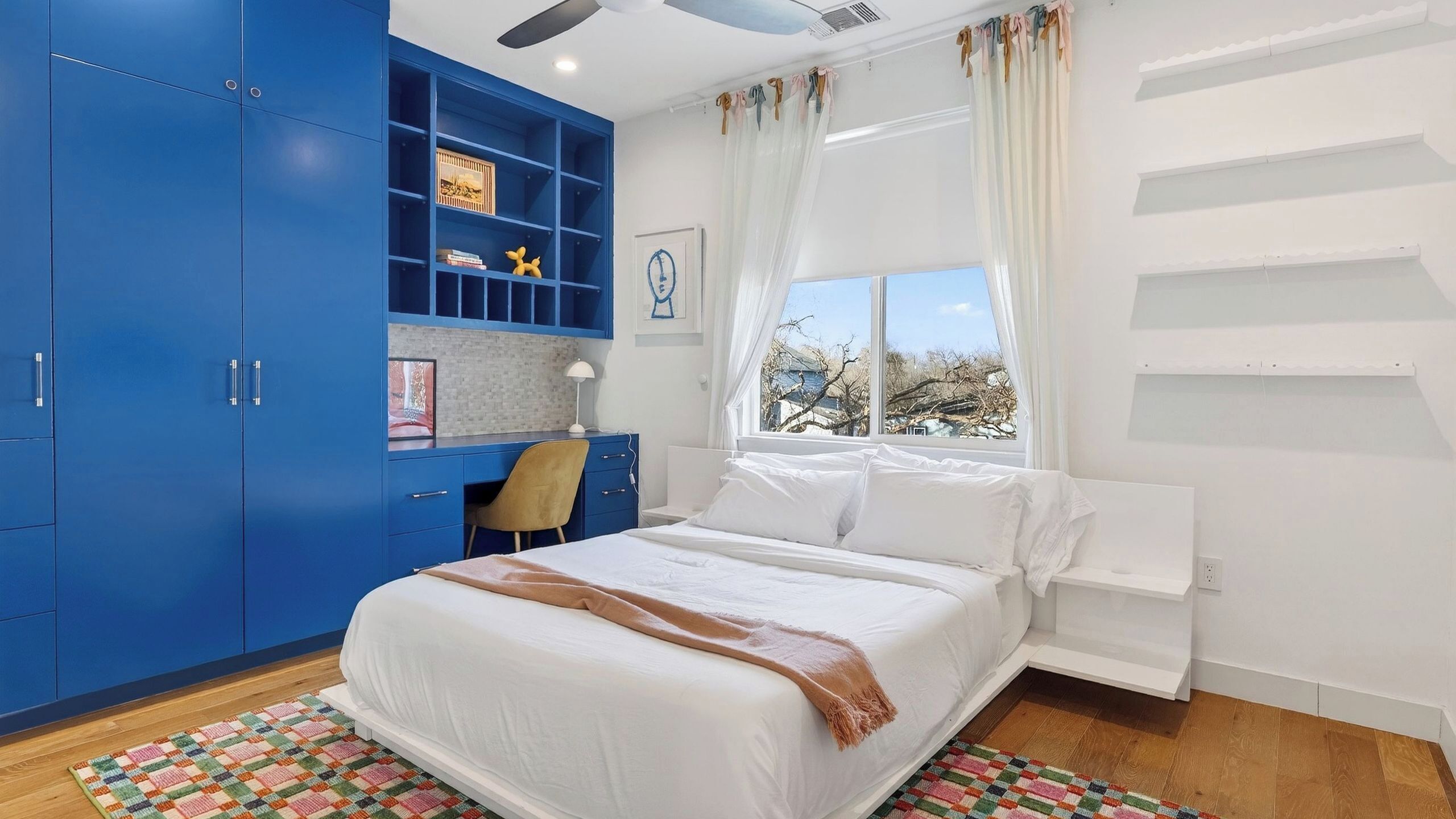 A bedroom with a bed, a desk, and a wardrobe.