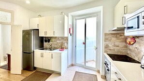 Een moderne keuken met witte kasten, een roestvrijstalen koelkast, een magnetron en een spoelbak.
