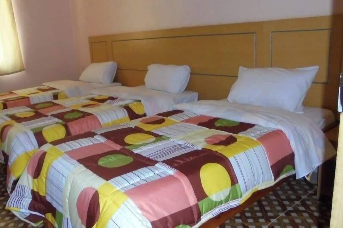A hotel room with two beds, each with a colorful quilt and white pillows.