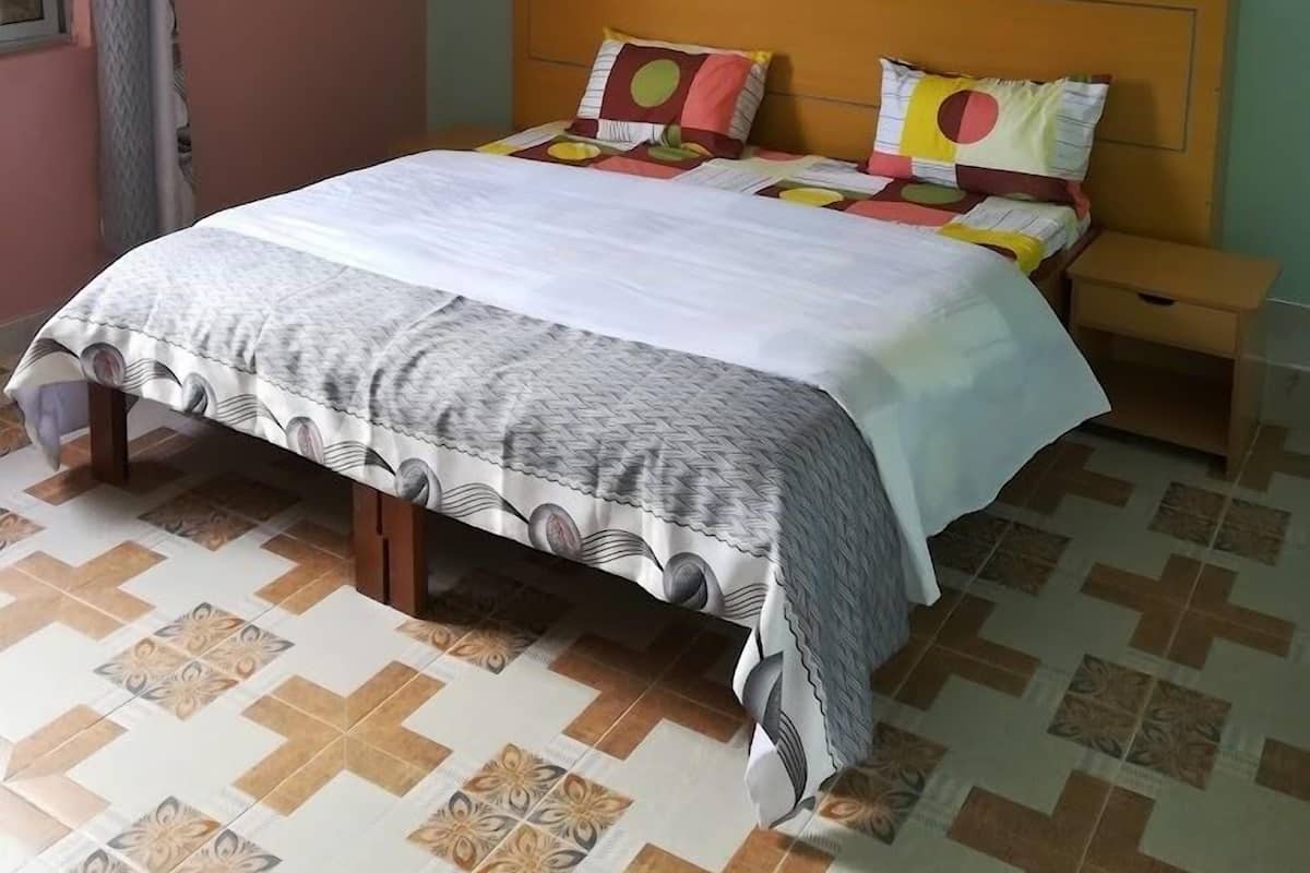 A bedroom with a bed, two bedside tables, and a window with curtains.
