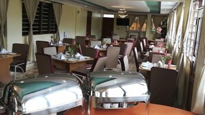 A dining area with round tables, chairs, and a buffet setup.