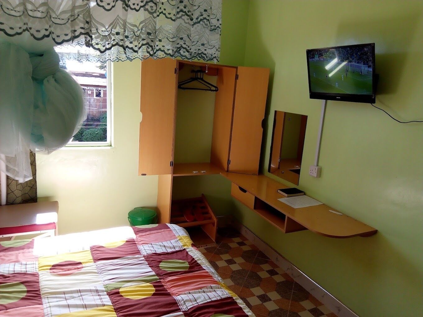 Una habitación con cama, armario, espejo y televisión.