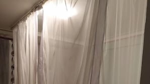 A bedroom with a bed covered by a sheer white canopy.