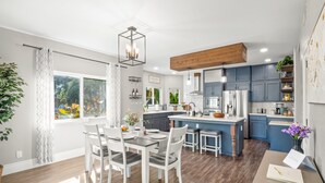 Una cocina moderna con una isla central, armarios blancos y una zona de comedor con mesa y sillas.