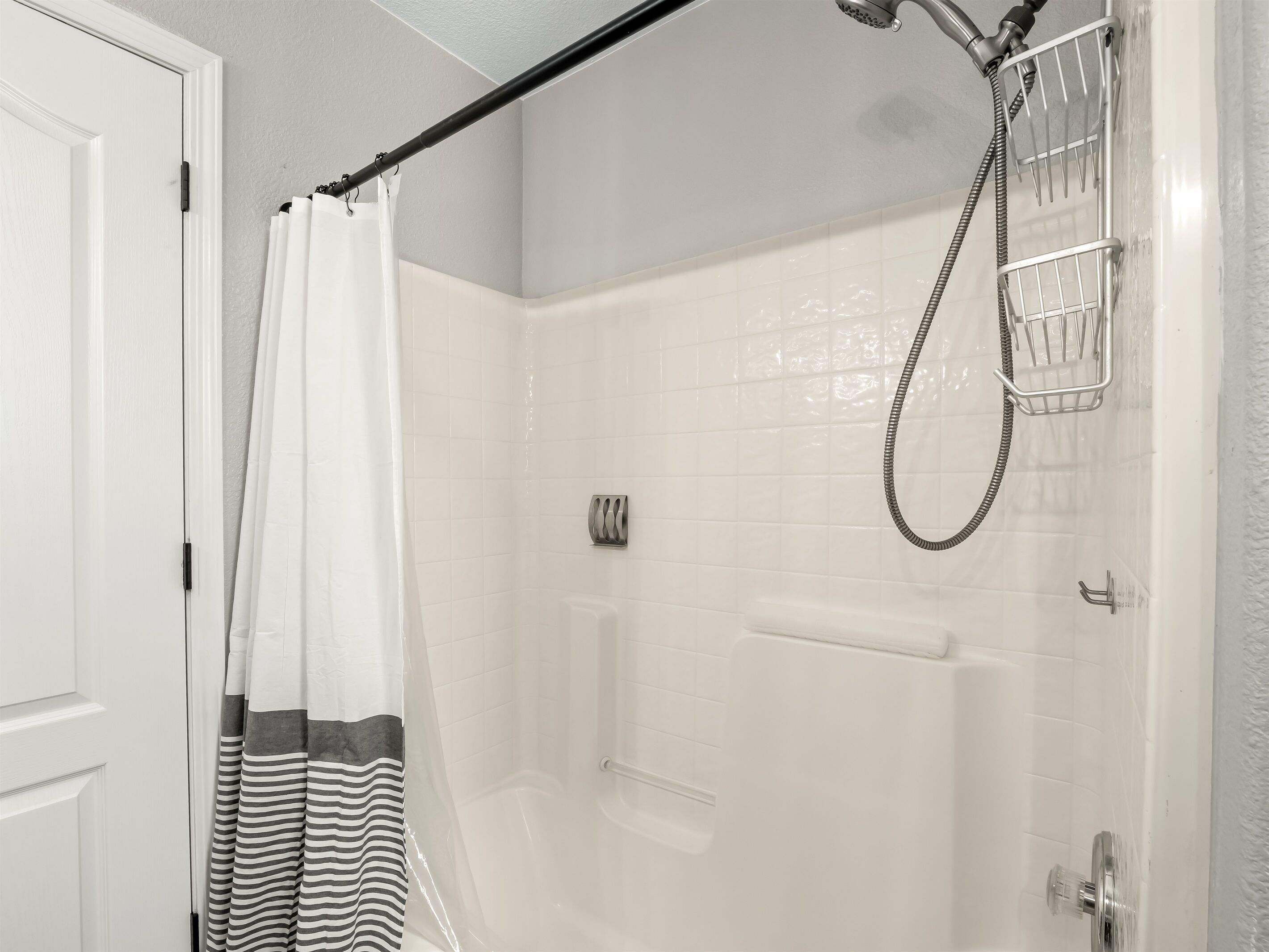 A shower area with a glass door, a showerhead, and a metal shower tray.