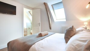 A bedroom with a bed, a window, a TV, and a door leading to a bathroom. - Belle location raffinée (Frênes, Tinchebray-Boc)