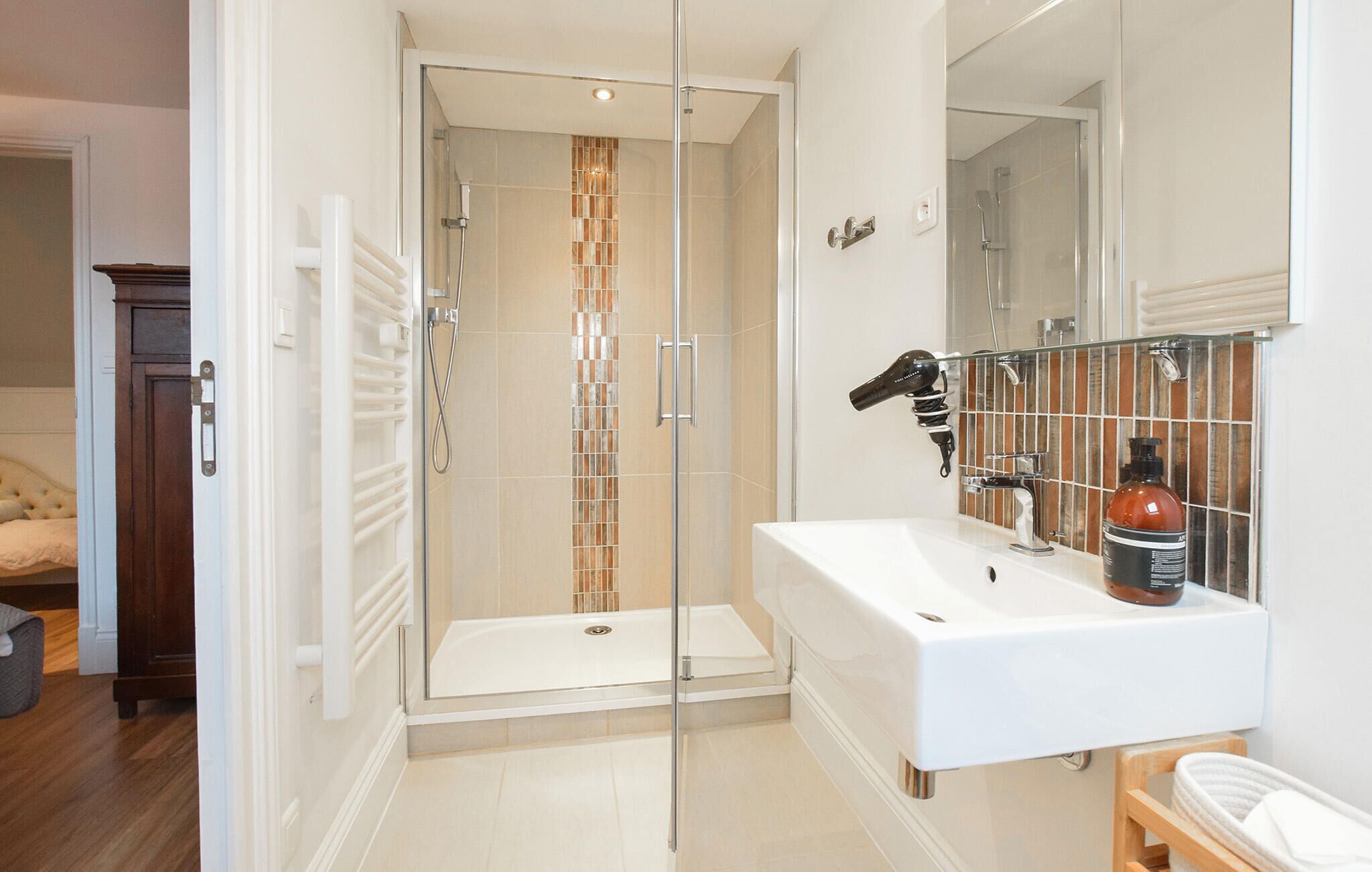 A modern bathroom with a glass-enclosed shower, a white sink, and a mirror above it.