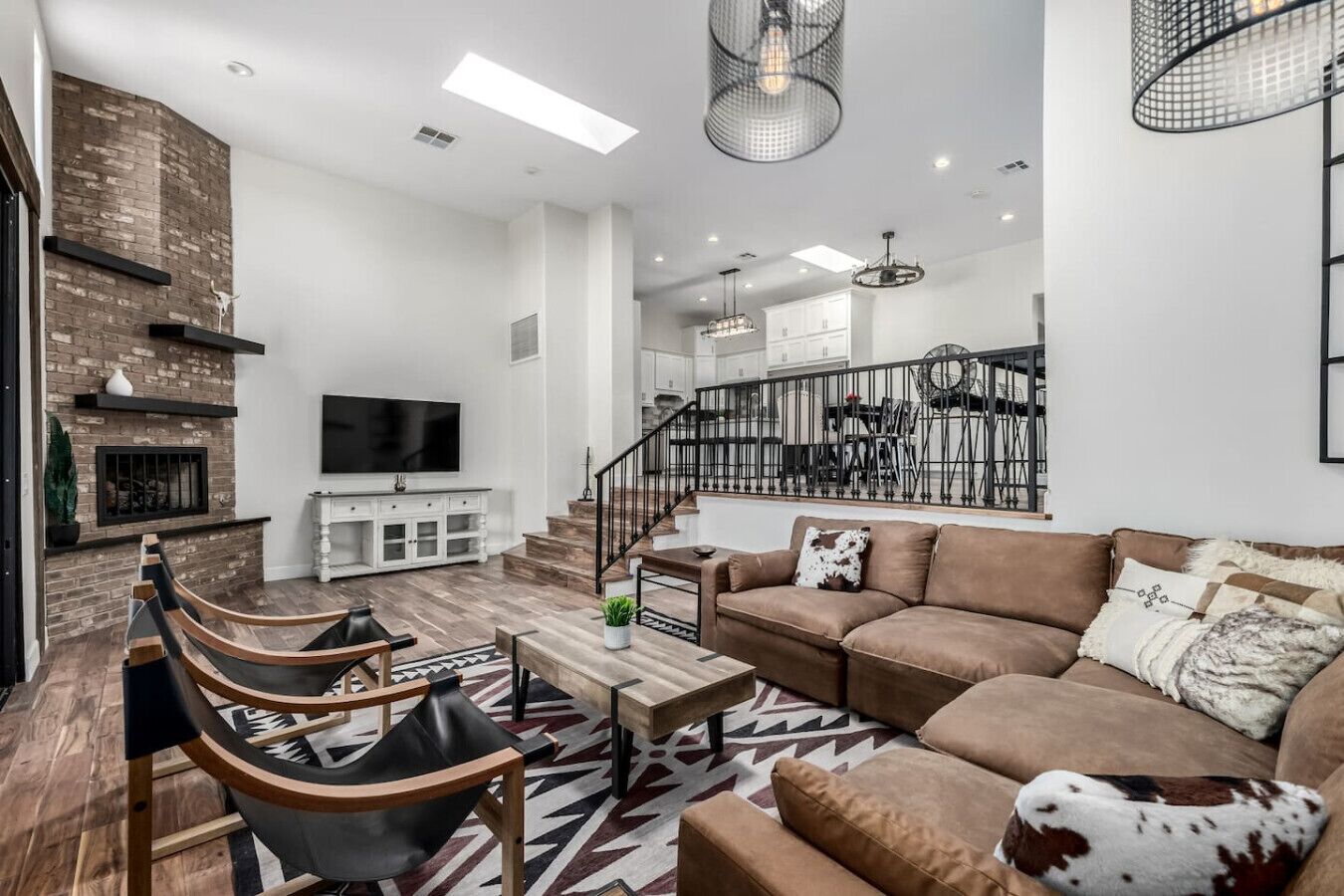 A modern living room with a fireplace, a staircase, and a dining area.