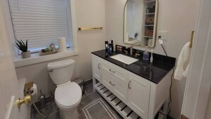 Een badkamer met toilet, wastafel, badkamermeubel en een spiegel met verlichting.
