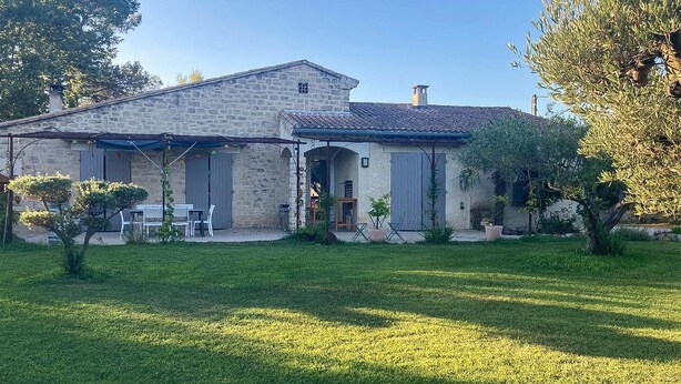 Una casa in pietra con tetto in tegole, un portico coperto e un piccolo giardino.