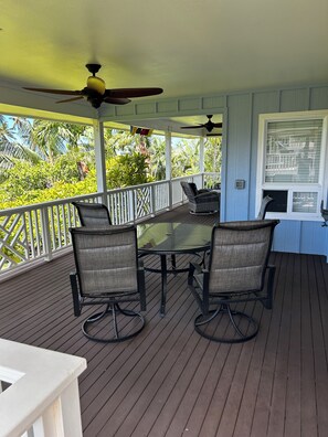 A covered outdoor area with a table and chairs, a ceiling fan, and a view of tropical vegetation. - Steps from the Beach! Exclusive 3/2.5 home in Poipu. Utilities Included! (Koloa)