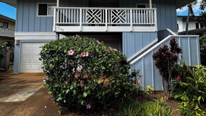A two-story house with a balcony, a garage, and a well-maintained garden with pink flowers. - Steps from the Beach! Exclusive 3/2.5 home in Poipu. Utilities Included! (Koloa)