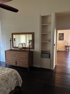 Ein Schlafzimmer mit einem Holzschrank, einem großen Spiegel und einer eingebauten Regallösung.