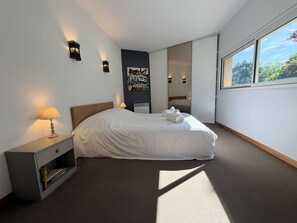 A bedroom with a bed, bedside tables, a nightstand, a poster, and a large window. - Le bois de saint-Cirq, private swimming pool (LE BUGUE)