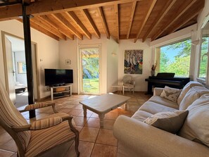 A living room with a television, sofa, armchair, piano, and a painting on the wall. - Le bois de saint-Cirq, private swimming pool (LE BUGUE)