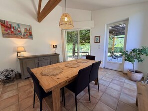 A dining area with a wooden table, black chairs, a hanging light fixture, and a view of the outdoors through a glass door. - Le bois de saint-Cirq, private swimming pool (LE BUGUE)