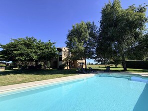A swimming pool with a clear blue water surface, surrounded by a well-maintained lawn and trees. - Le bois de saint-Cirq, private swimming pool (LE BUGUE)