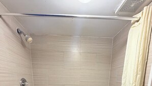 A bathroom with a bathtub, a shower curtain, and tiled walls. - Royal INN  (Richmond)