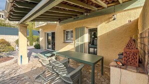 Une terrasse extérieure avec une table et des chaises, une pergola et une clôture décorative en métal.