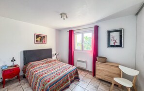 A bedroom with a bed, a nightstand, a chair, a dresser, a window with curtains, and a ceiling fan. - Maison Avec Piscine 1 (Saint raphael)