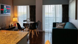Habitación de hotel con comedor, sofá y televisor en la pared.