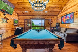 A pool table in a wooden room with a view of mountains through a glass door. - 6 BR, large indoor pool, full arcade, views, cinema, and gameroom. Sleeps 25+ (Pittman Center)