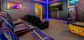 A room with multiple reclining massage chairs, a television screen, and a neon sign. - 6 BR, large indoor pool, full arcade, views, cinema, and gameroom. Sleeps 25+ (Pittman Center)