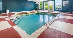 Ein Hallenbad mit Schachbrettmuster auf dem Boden, einer Poolleiter und Blick ins Freie durch eine Tür.