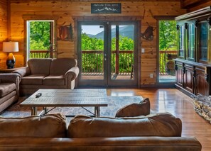 A cozy cabin interior with a sofa, a coffee table, and a TV. - 6 BR, large indoor pool, full arcade, views, cinema, and gameroom. Sleeps 25+ (Pittman Center)