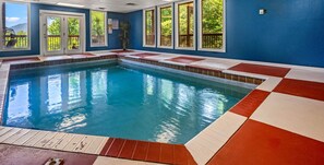 An indoor swimming pool with a blue tiled floor and a clear view of the surrounding trees through the windows. - 6 BR, large indoor pool, full arcade, views, cinema, and gameroom. Sleeps 25+ (Pittman Center)