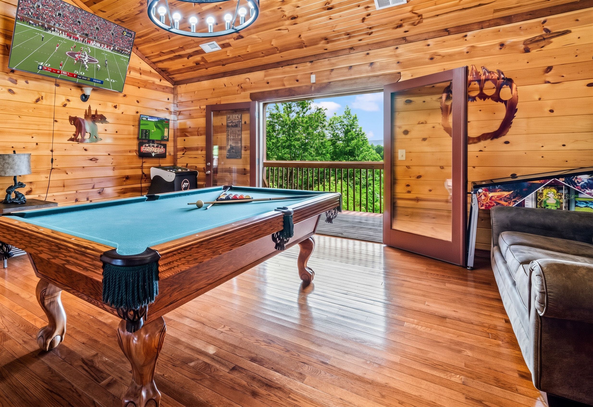 Une table de billard dans une pièce en bois, avec un balcon et une vue sur les arbres.