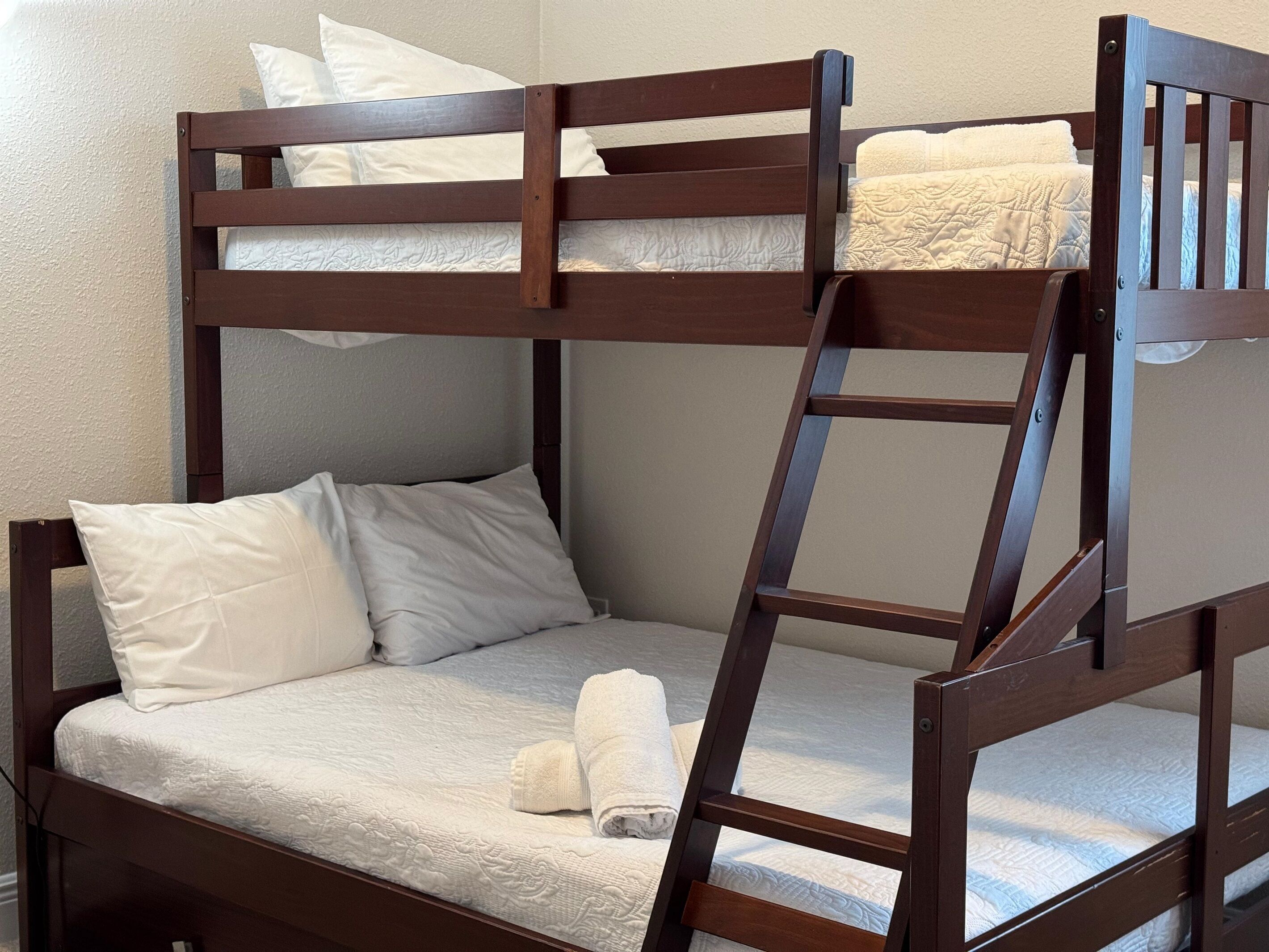 Una cama individual superpuesta con escalera, ropa de cama blanca y almohadas.