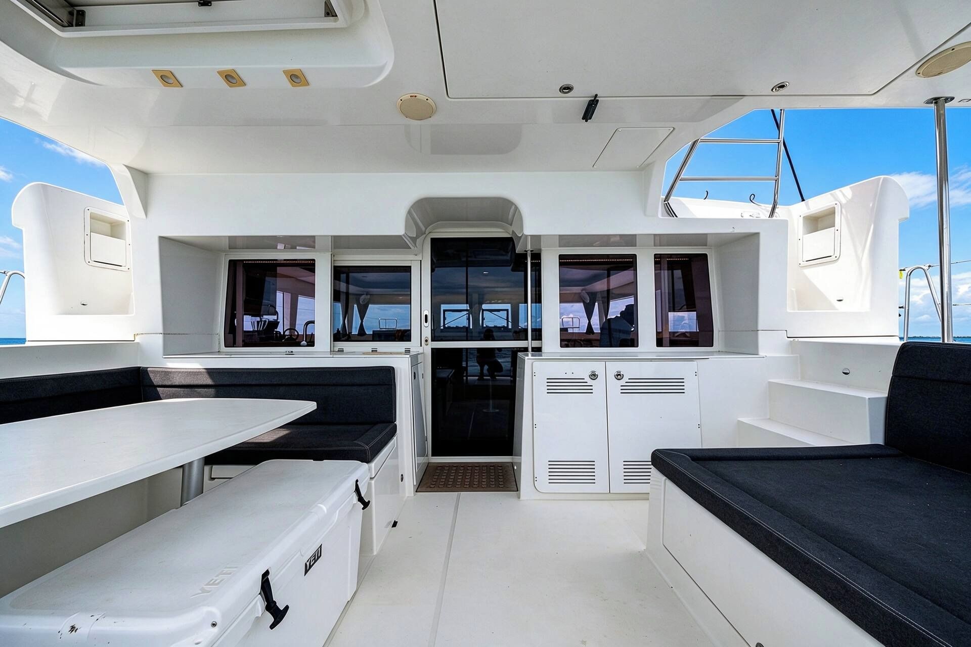 A boat's interior with a central seating area, a table, and a view through the windows.
