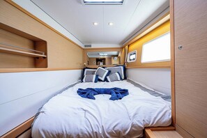 A compact, well-lit interior with a bed, a small window, and a mirror. - 46ft Catamaran · 4 Ensuite Cabins · Pool & Beach (Key West)