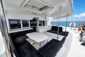Das Deck eines Bootes mit Sitzgelegenheiten, einem Tisch und Blick aufs Meer.