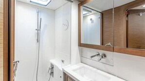 Une salle de bain moderne avec une douche à l’italienne, un grand miroir et un lavabo blanc.