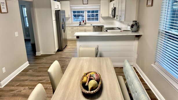 A modern kitchen with white cabinets, a stainless steel refrigerator, and a dining area with a wooden table and chairs. - Duplex in the Caribbean Paradise (Panama City)