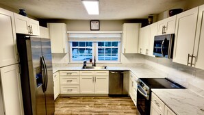 A modern kitchen with white cabinets, a stainless steel refrigerator, a dishwasher, and a microwave. - Duplex in the Caribbean Paradise (Panama City)