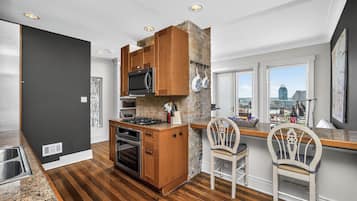 A modern kitchen with a stone accent wall, wooden cabinets, a built-in oven, and a city view through large windows.