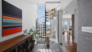 Eine moderne Treppe mit Blick auf die Stadt, ein Holztischchen mit einem farbenfrohen, abstrakten Gemälde und ein Steinboden.