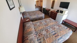 Ein Hotelzimmer mit zwei Betten, einem Schreibtisch, einem Stuhl, einem Fernseher, einer Mikrowelle und einem Schminktisch.