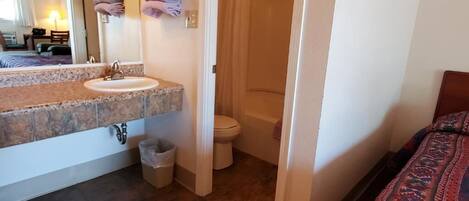 Et badeværelse med vask, toilet og bruser.