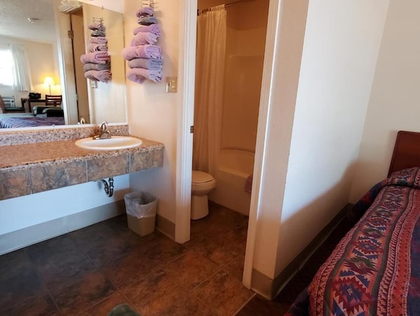 A bathroom with a sink, toilet, and shower. - Riverside Inn (Glendive)